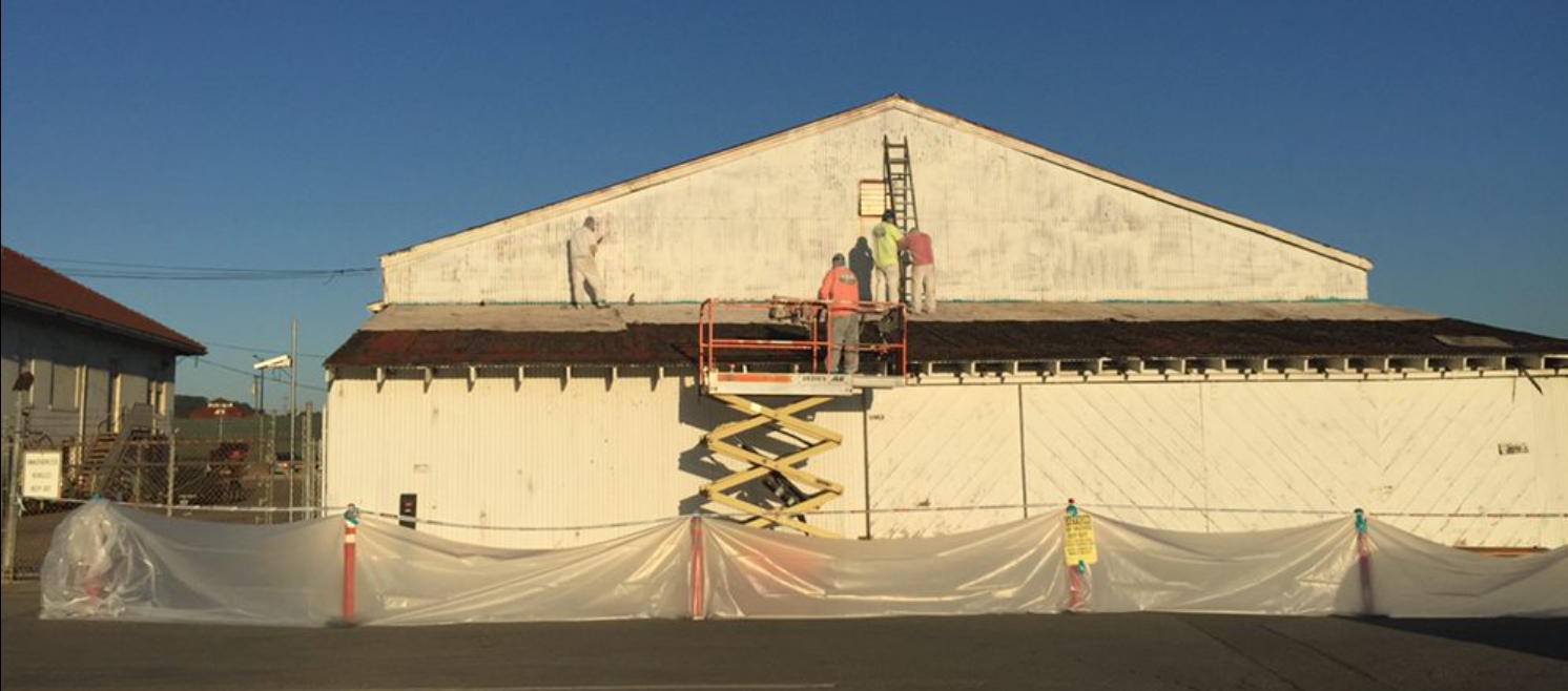 Painting crew on a scissor lift repainting a commercial building gable